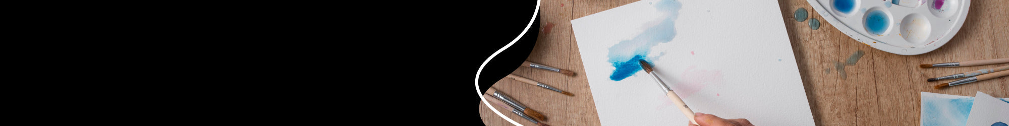 hand with a paintbrush which do some gouache painting on watercolour paper