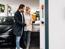 Ehemann erklärt seiner Frau die einfache Benutzung der an einer Wand montierten mobile Wallbox go-e  gemini flex 11kw 